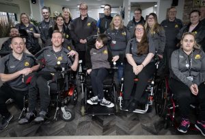 A large group of the happy smiles training team wearing a range of black and grey happy smiles uniform with a yellow happy smiles logo on the chest, all huddled together smiling