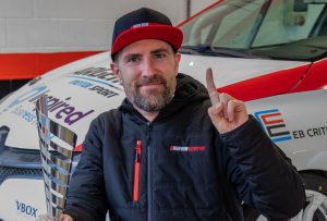 Man stood in front of race car celebrating victory