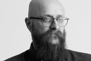 A picture of Martin - a middle aged man with a shaved head and long beard and glasses